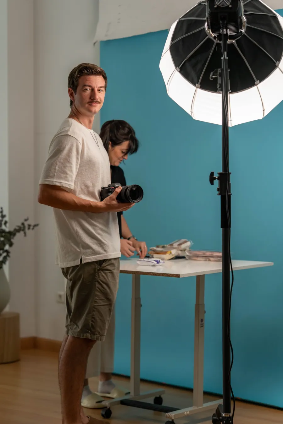 Andrey Shamray con la cámara en un rodaje de producto en estudio, junto a una compañera preparando el bodegón